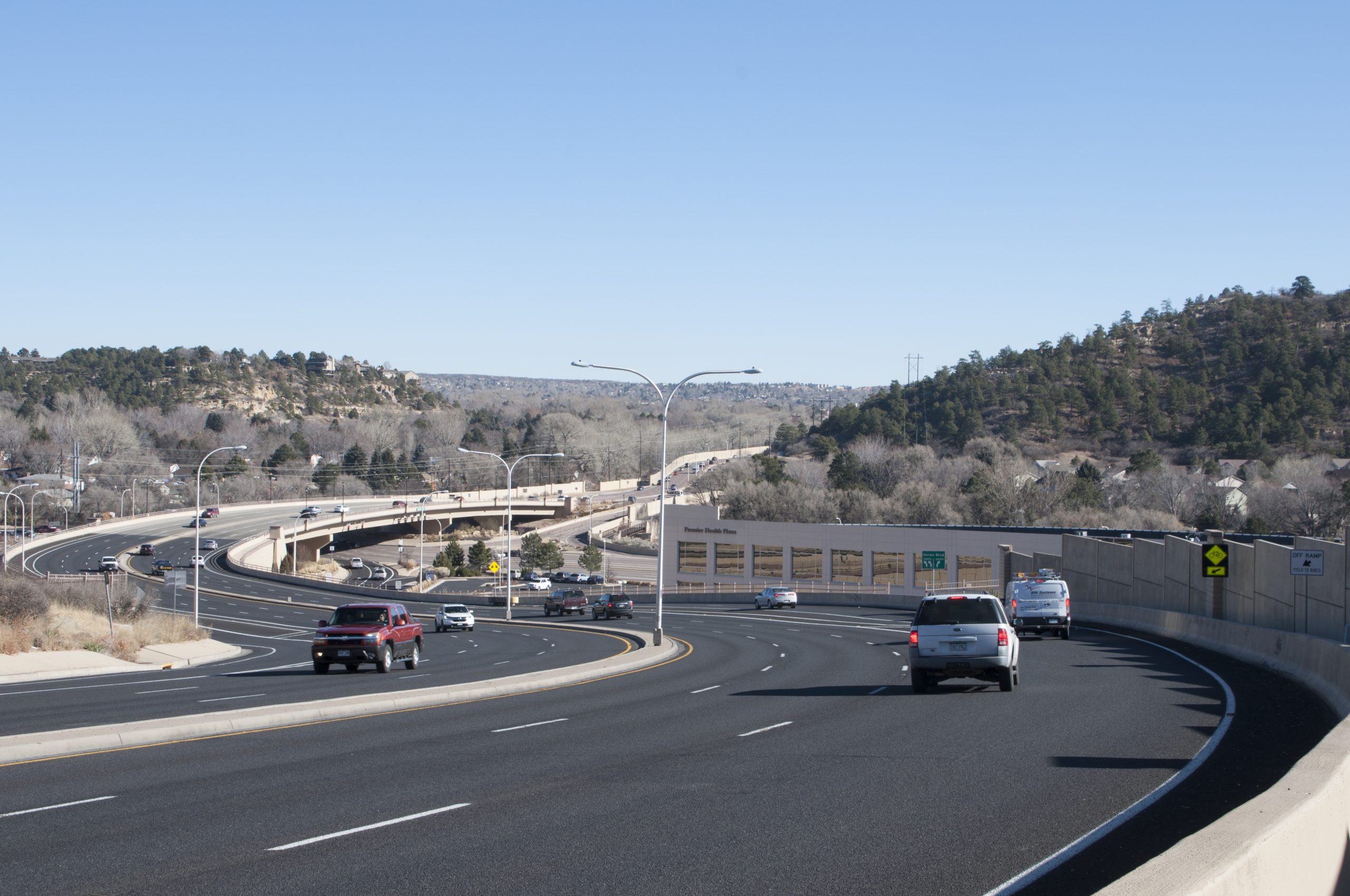 Cars driving away on a three-lane paved road.