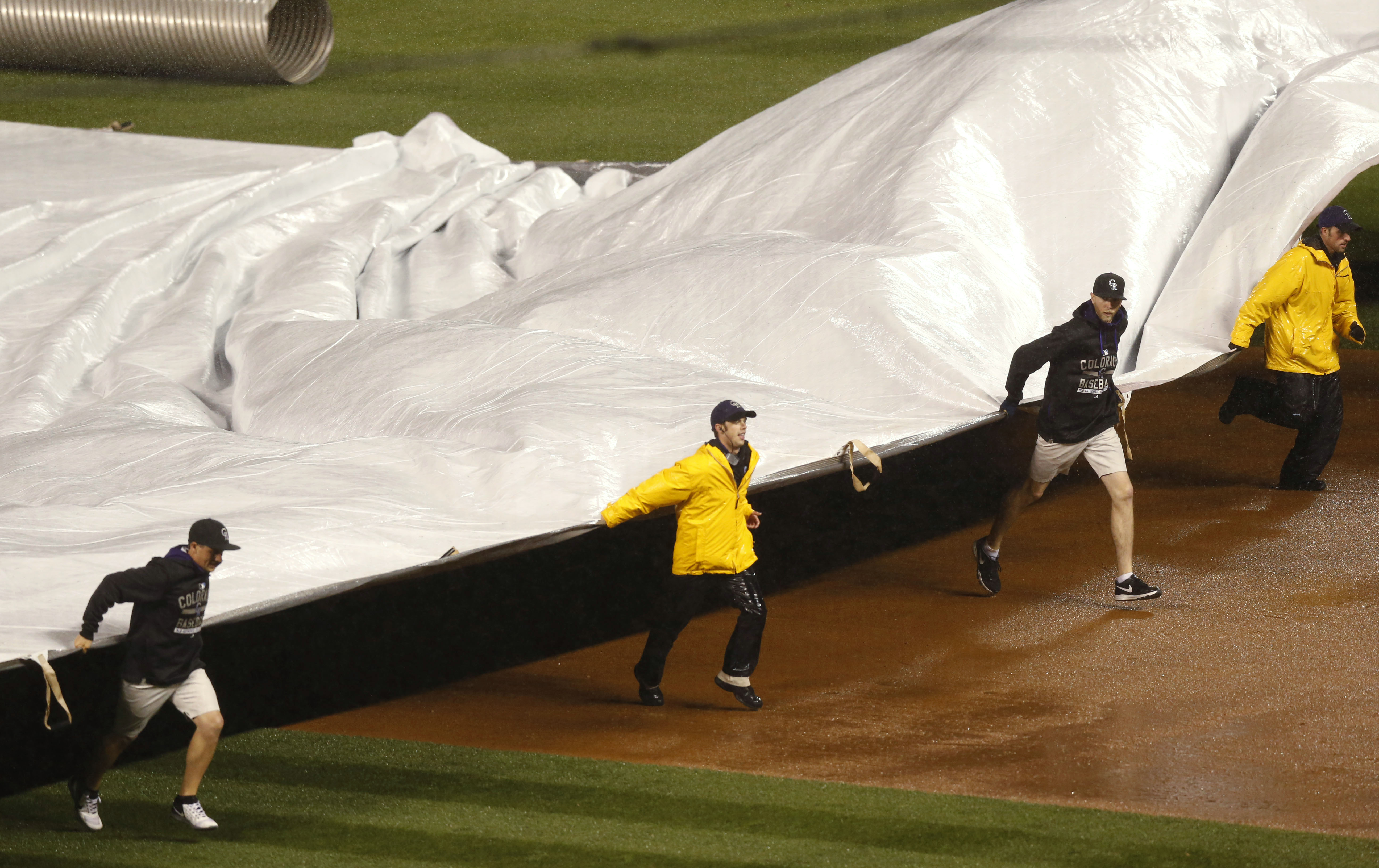 Photo: Grounds crew pull the tarp, rain delay, Colorado Rockies vs. San Francisco Giants May 22 (AP)