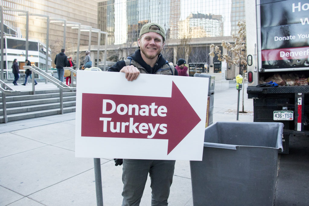 Volunteer Brigham Ray holds a sign during the Denver Rescue Mission's turkey drive outside of Republic Plaza, Nov. 2, 2018. (Kevin J. Beaty/Denverite)