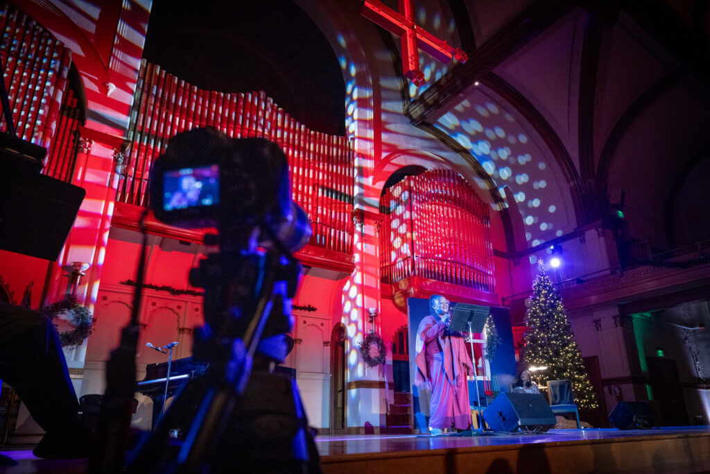 Poet Confidence Omenai on stage at the Colorado Matters Holiday Extravaganza