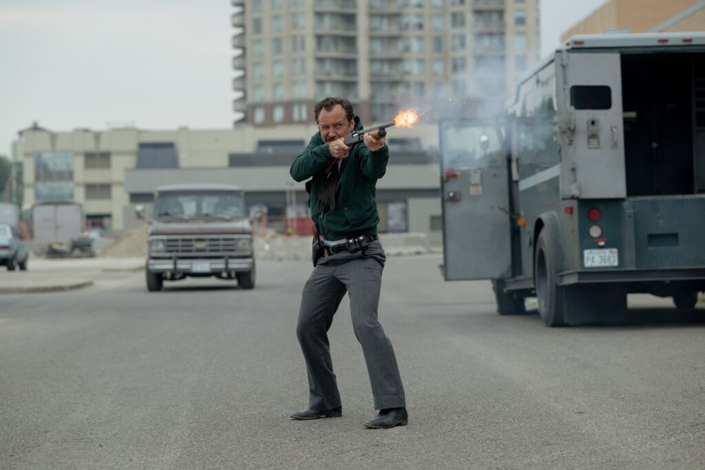 Photo shows actor Jude Law in a movie clip firing a gun in a street at a suspect as FBI agent Terry Husk in the movie "The Order."