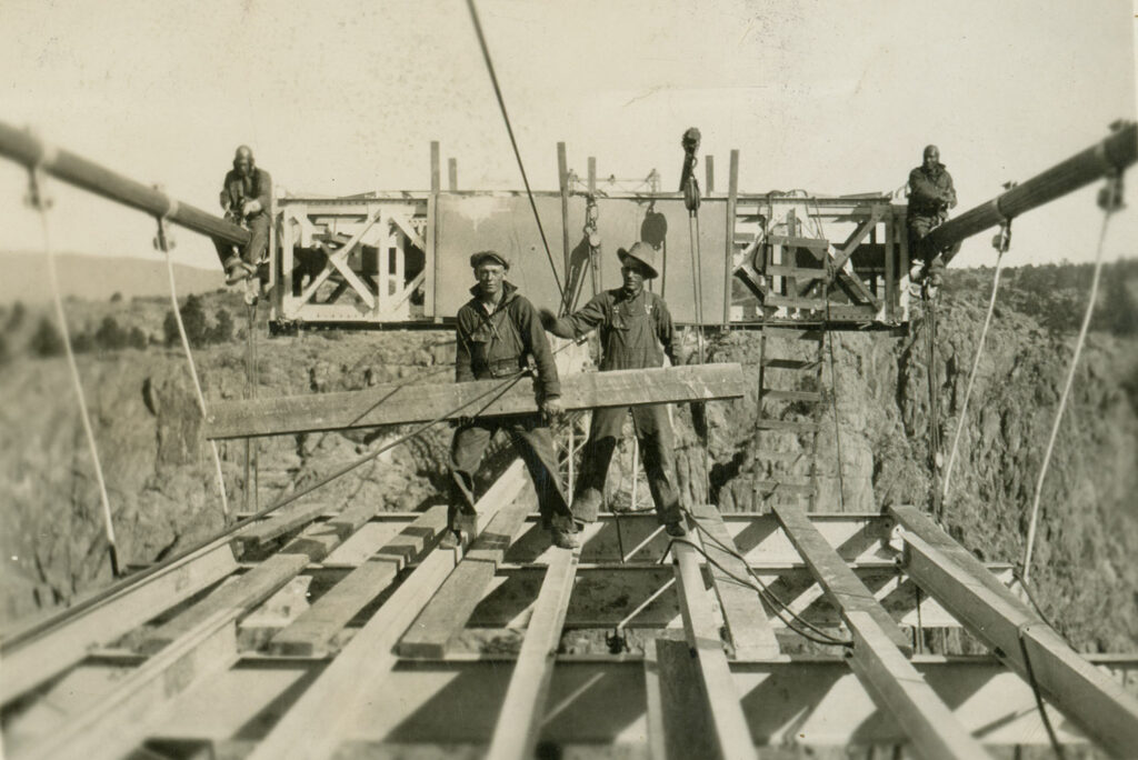 black and white image of construction workers on a bridge