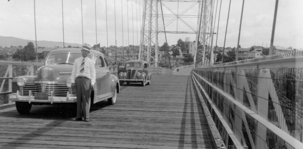 black and white image of old cars crossing the bridge