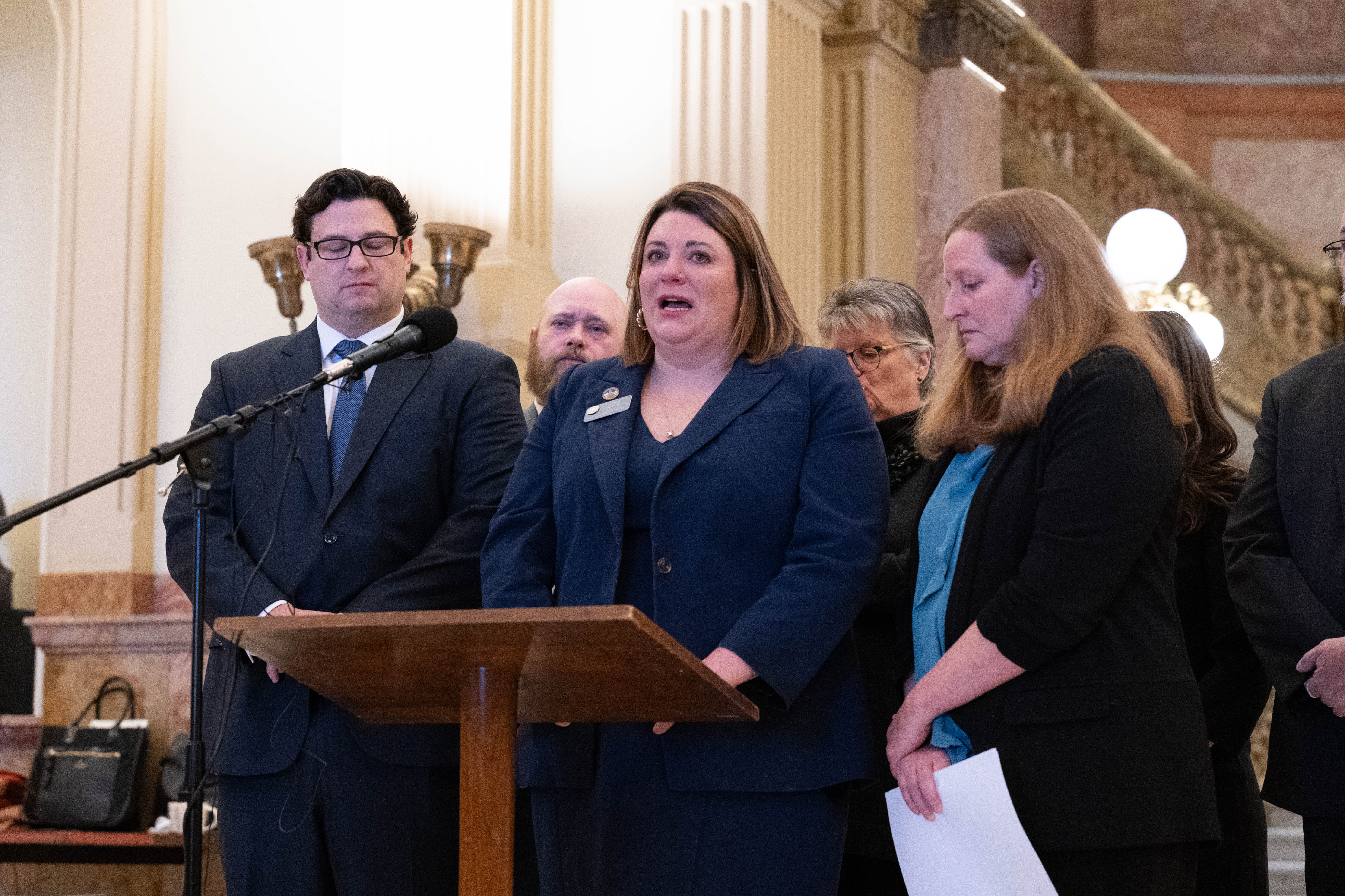 State Rep. Jenny Willford stands at a lecturn, flanked by her lawyers at a capitol press conference to discuss her lawsuit against Lyft.