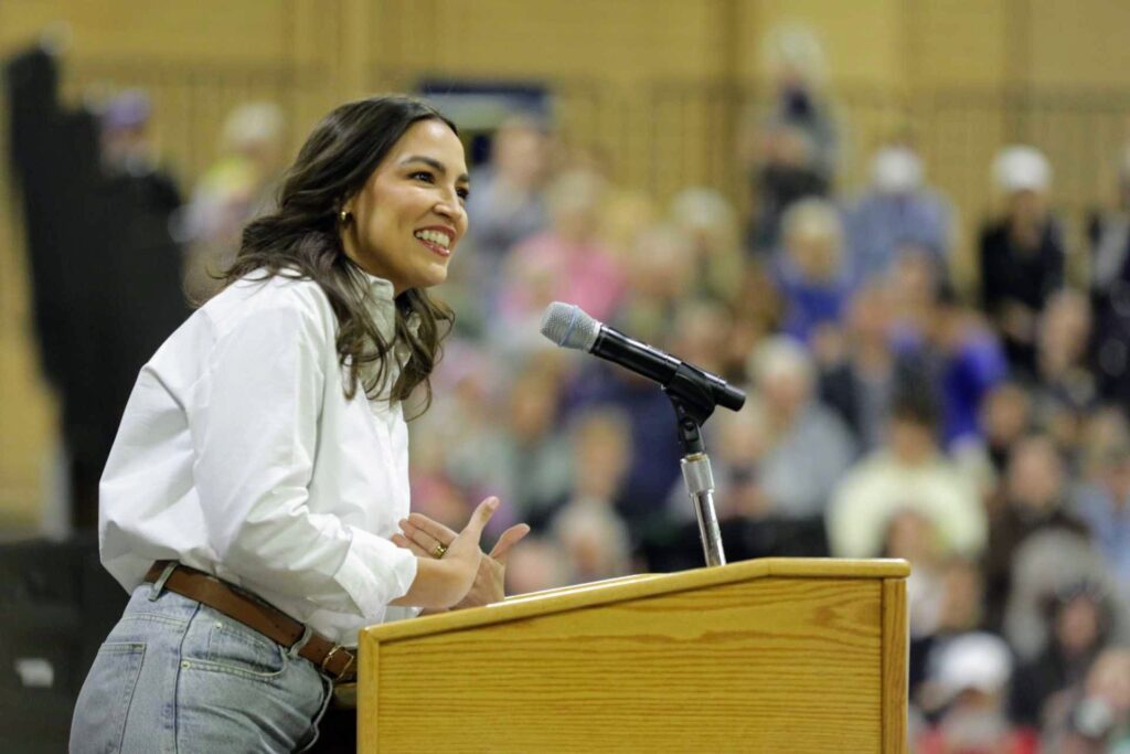 Alexandria Ocasio-Cortez speaks from a podium at the Bank of Colorado Arena in Greeley