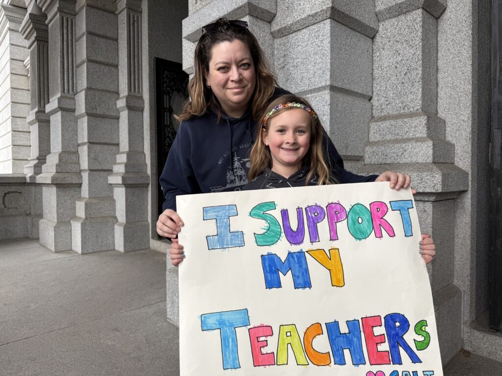 A mother and daughter hold a sign.