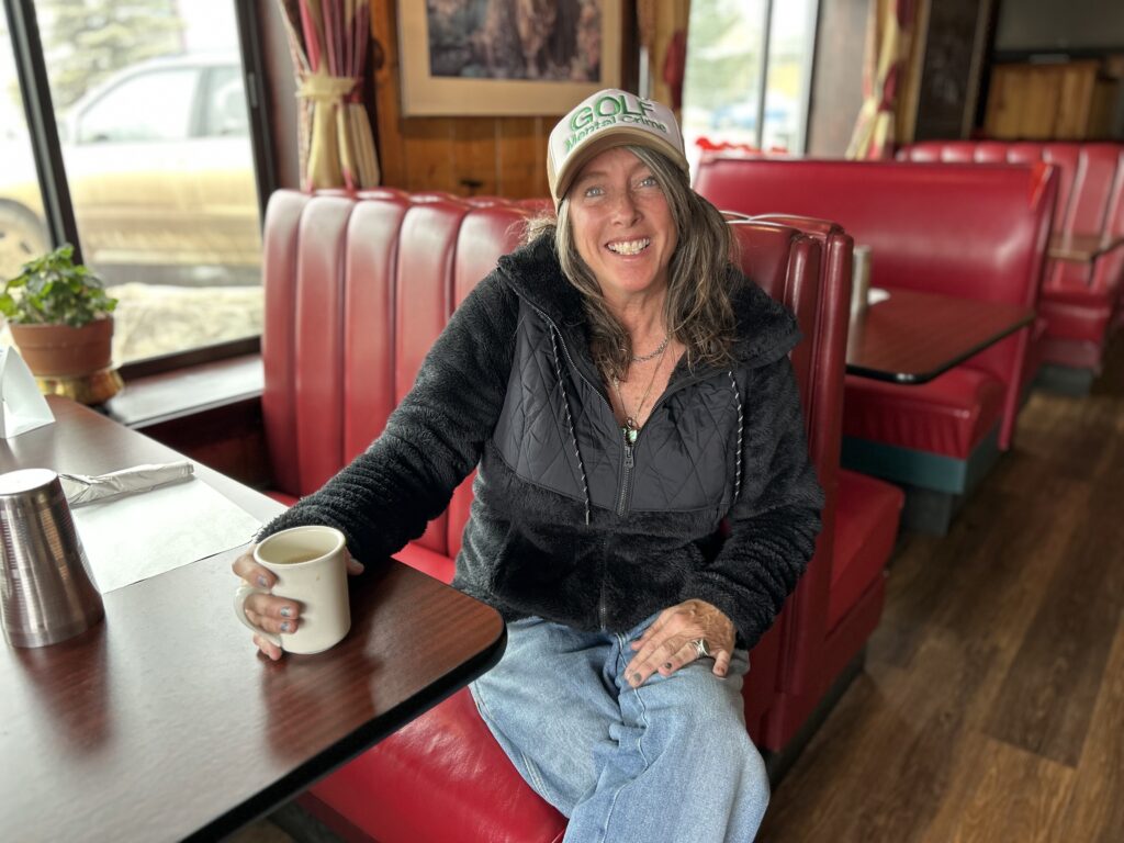 Amanda MacDonald sits at a restaurant in Nederland, Colorado holding a mug of coffee.