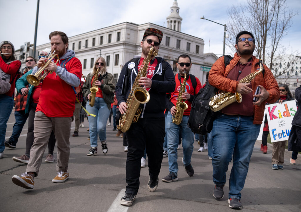 People play instruments walking down the street as part of the protest.