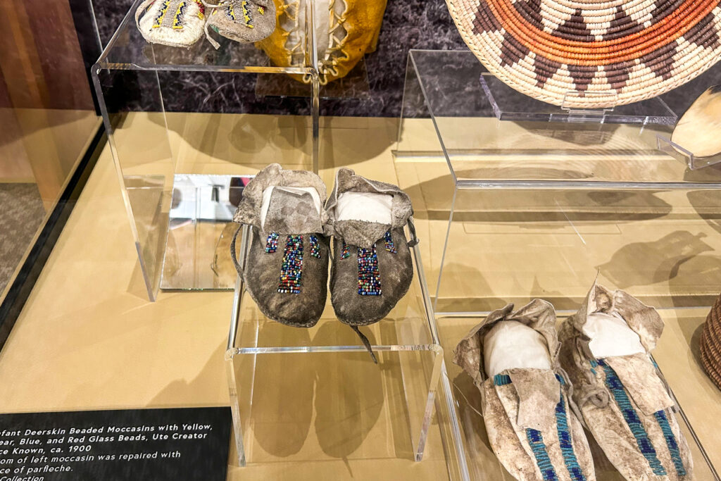 Photo shows moccasins and a basket on display at the Pioneers Museum in Colorado Springs elevating Ute culture and history.