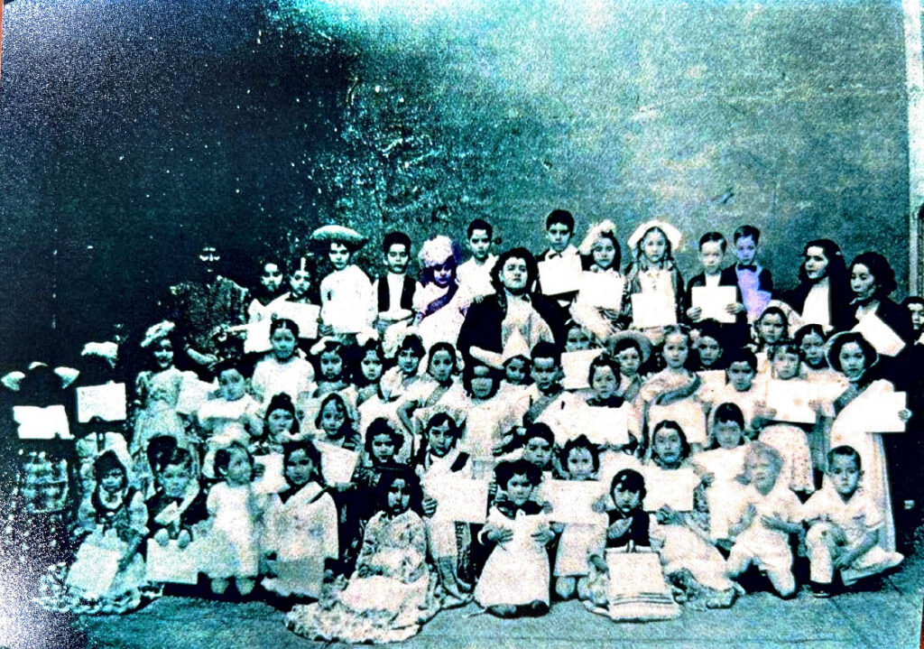 Group photo of dozens of children and adults dressed formally, gathered together.