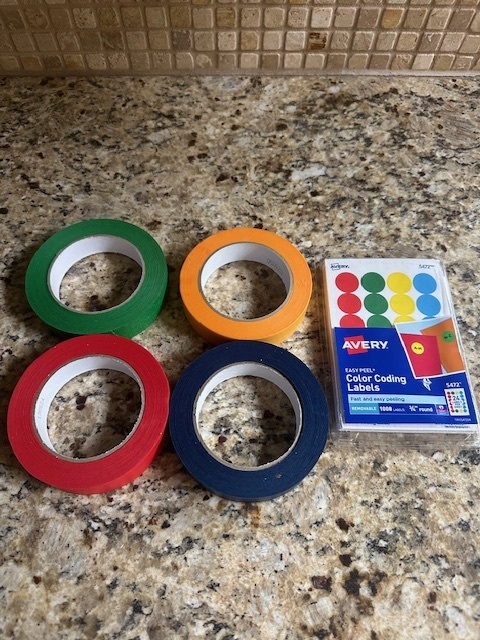 Photo shows four rolls of colored tape and a package of small colored dot stickers.