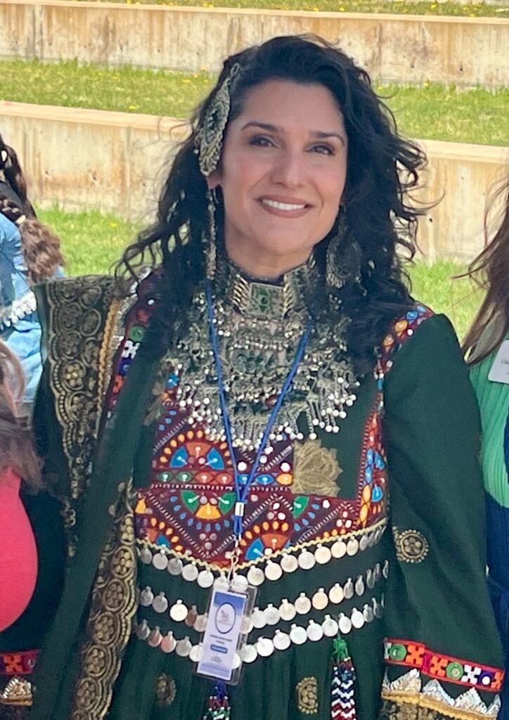 Woman smiling wearing green traditional Afghan dress