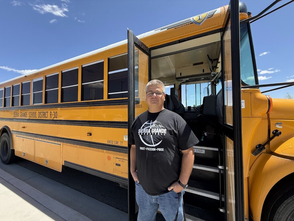 A man stands next to a bus.