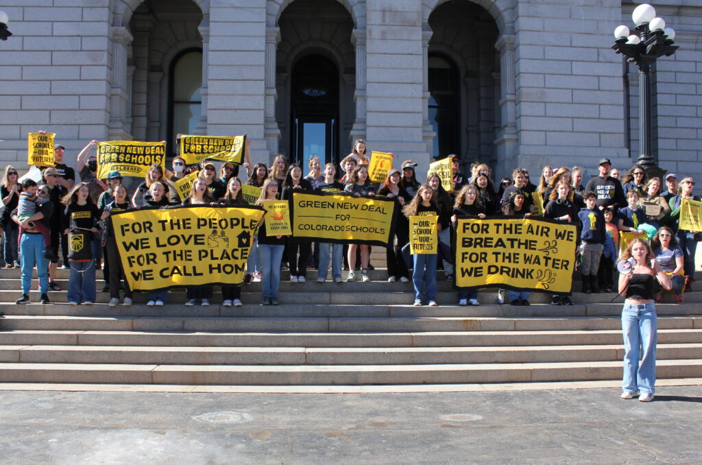 A group of about three dozen high school students stand on the steps of the Colorado Capital holding signs and banners that say Green New Deal for Schools and Our Schools Our Futures.