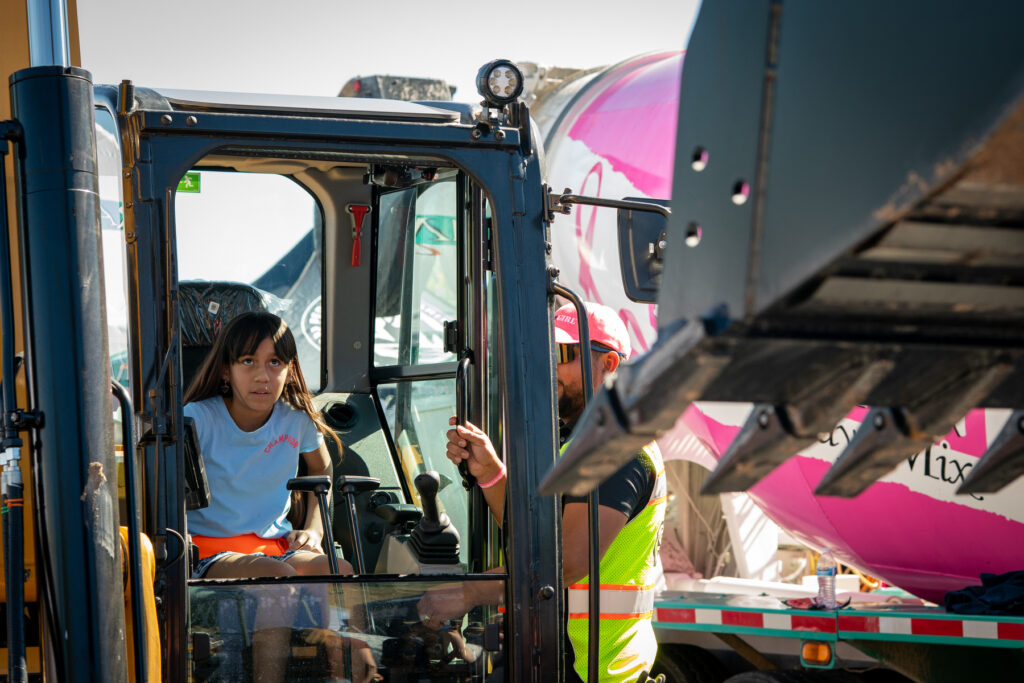 A young girl triues her hand at maneuvering a mini excavator