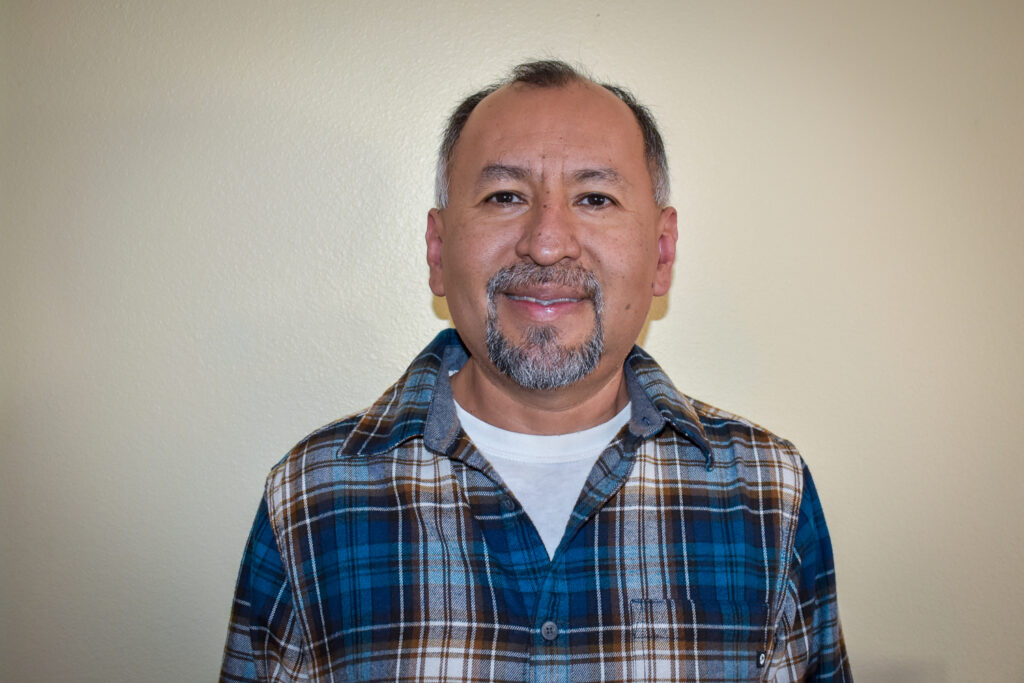 Smiling man in plaid shirt looking at camera