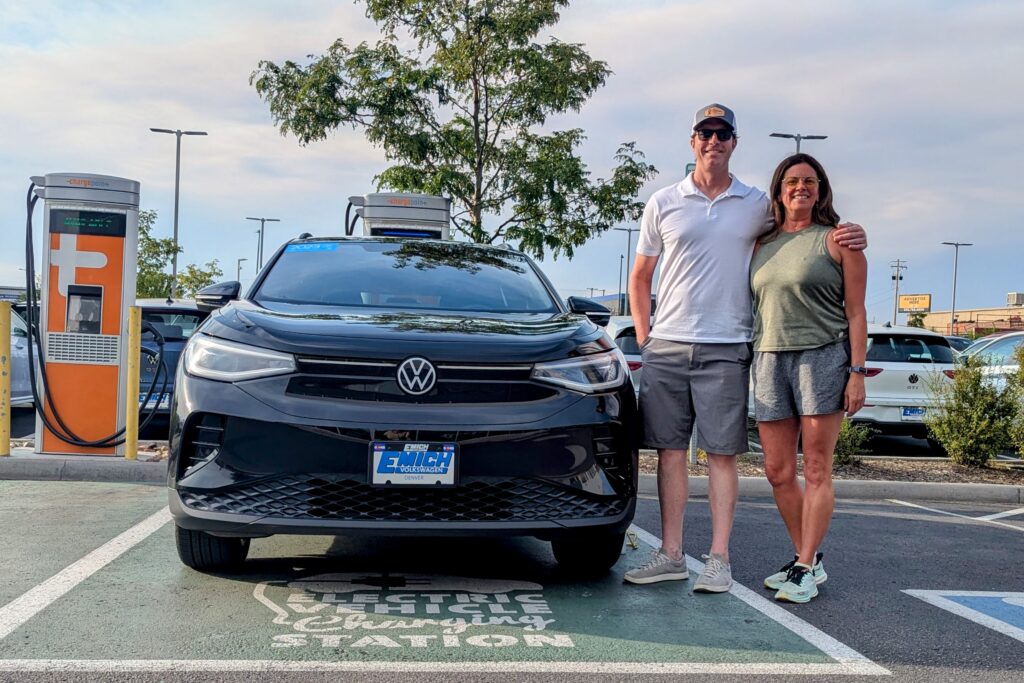 A couple besides a Volkswagen EV in Denver