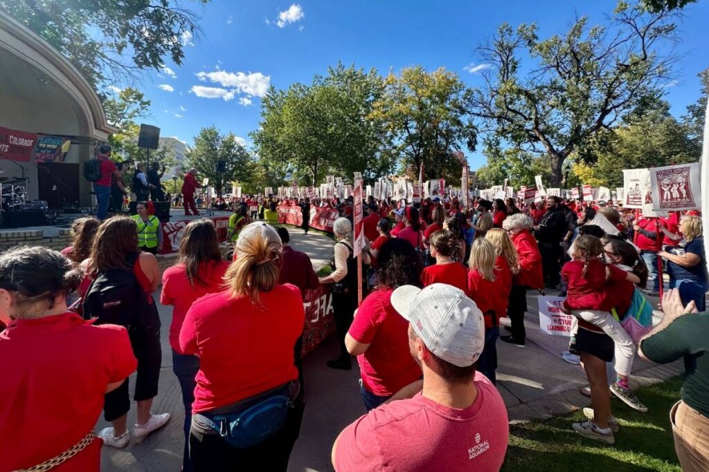 A wide shot of a large rally crowd, mostly wearing red
