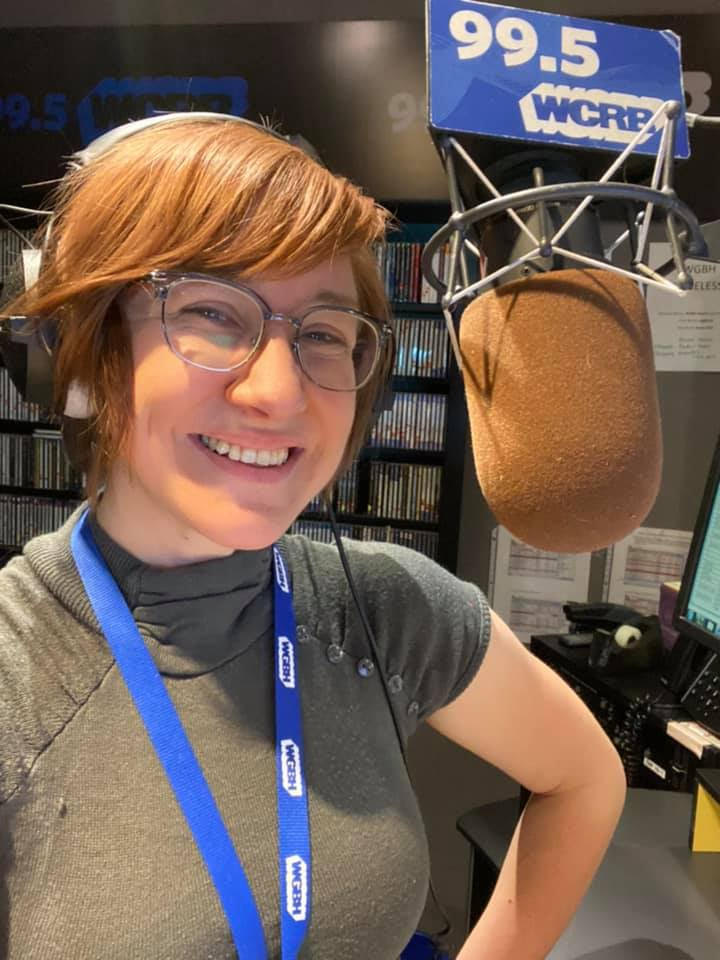 Radio host Jessie Jacobs takes a smiling selfie of her behind the mic at WCRB in Boston.