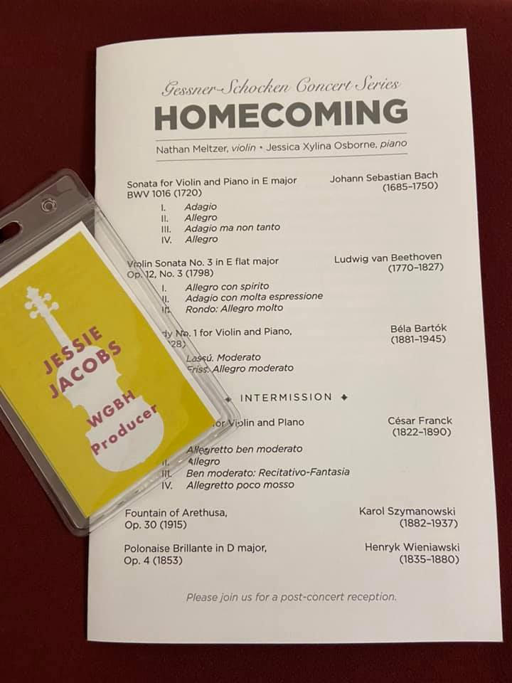 A concert program for a classical recital called "Homecoming." On top of the program is a producer badge.