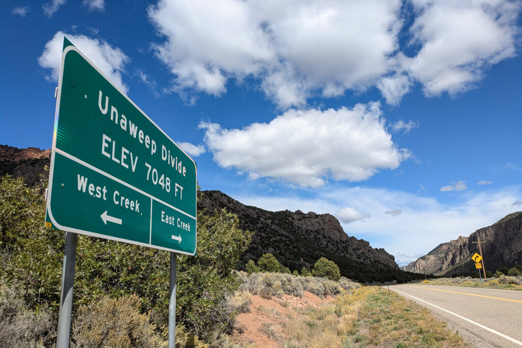 The roads sign for Unaweep Divide is shown. The divide sits at 7,048 feet above sea level and denotes the separation of East Creek and West Creek.