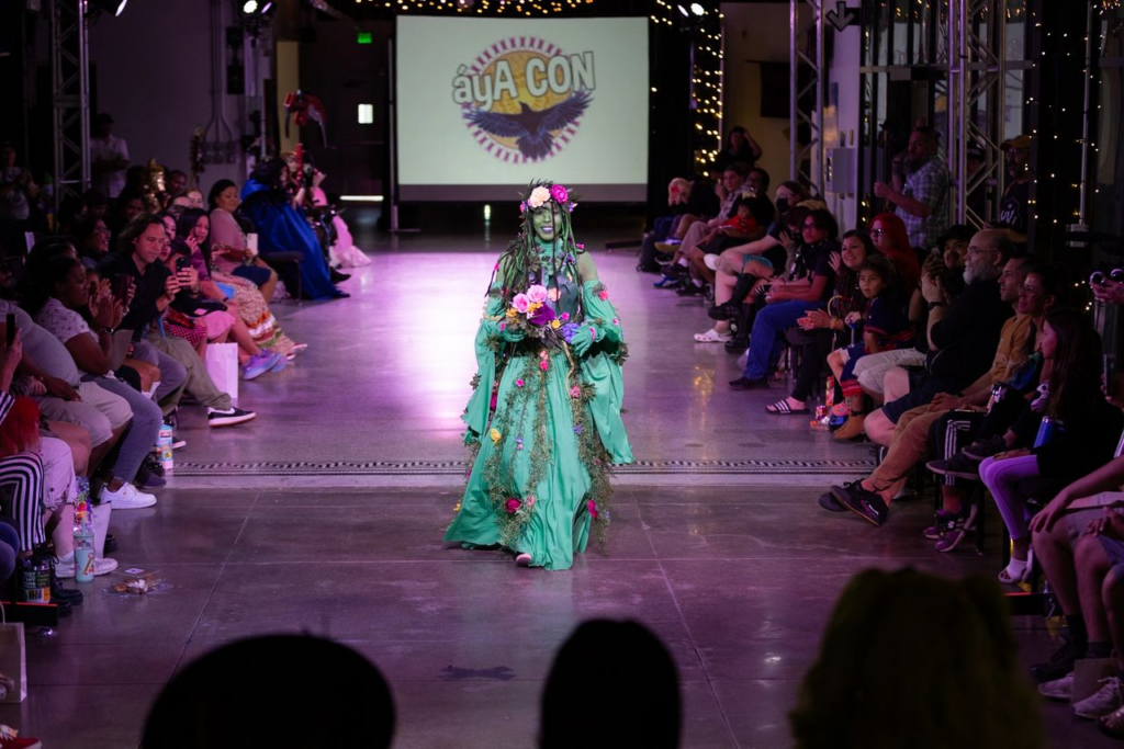 A model in a green outfit walks down a runway