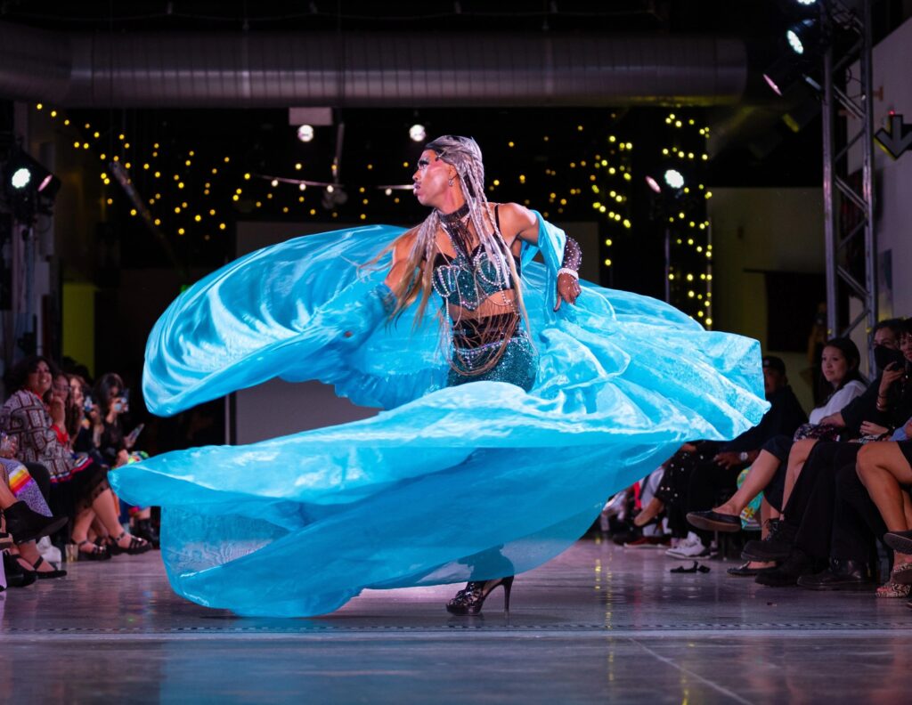 A person in a blue swirling skirt twirling on stage