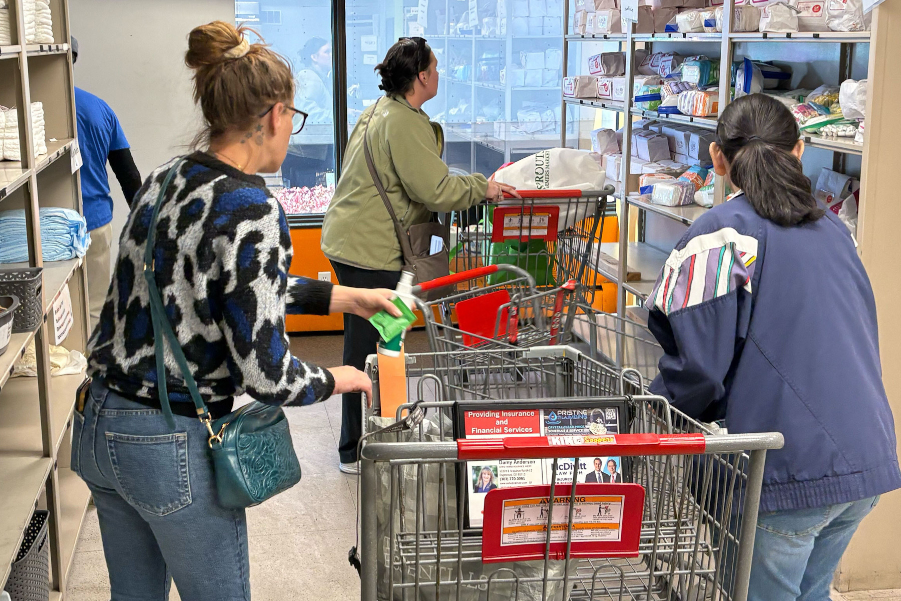 People with shopping carts survey grocery shelves