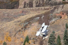 The image depicts a large, white truck crashing into a hillside, The scene is set in a mountainous area.