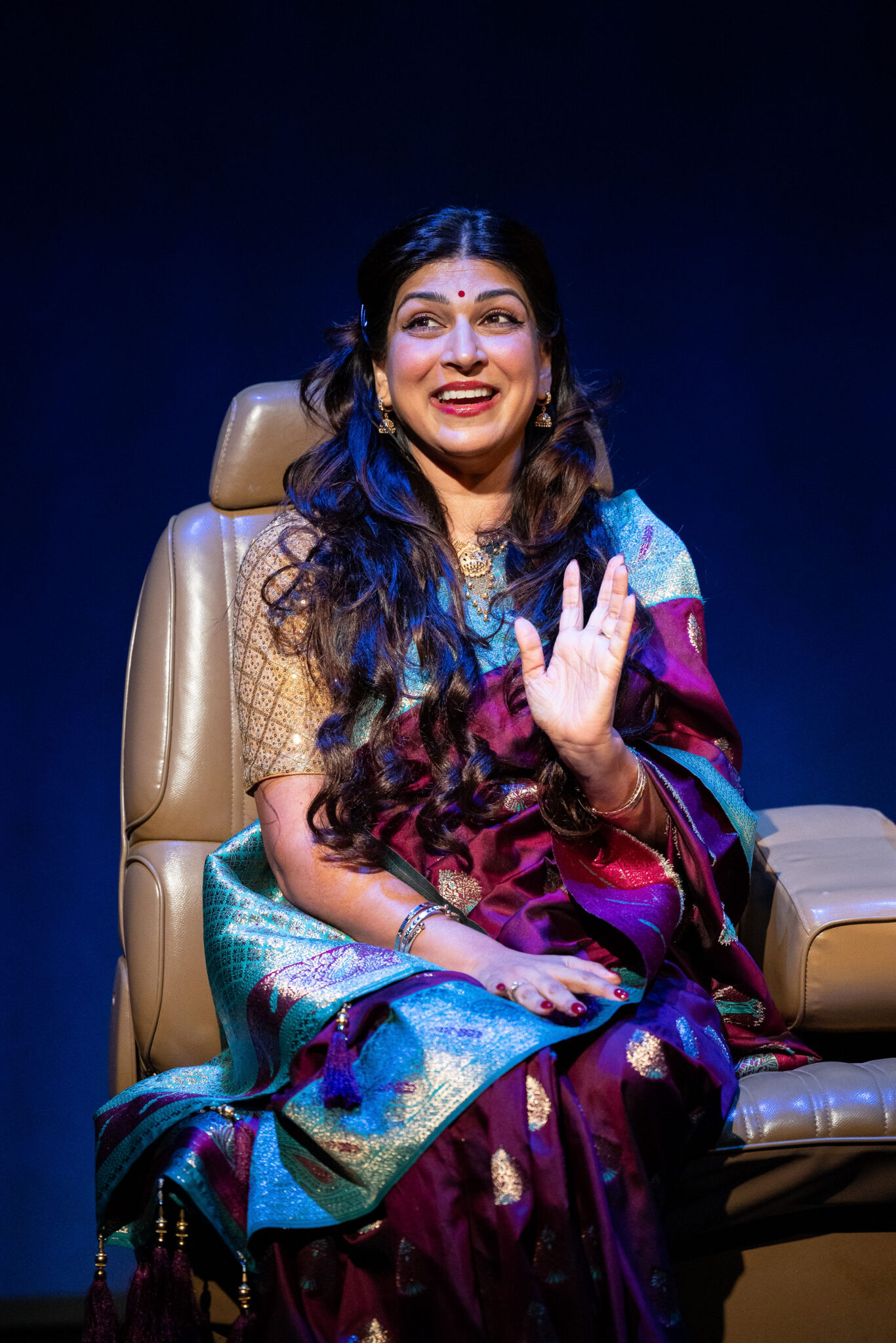 Woman sits in car with saree on.