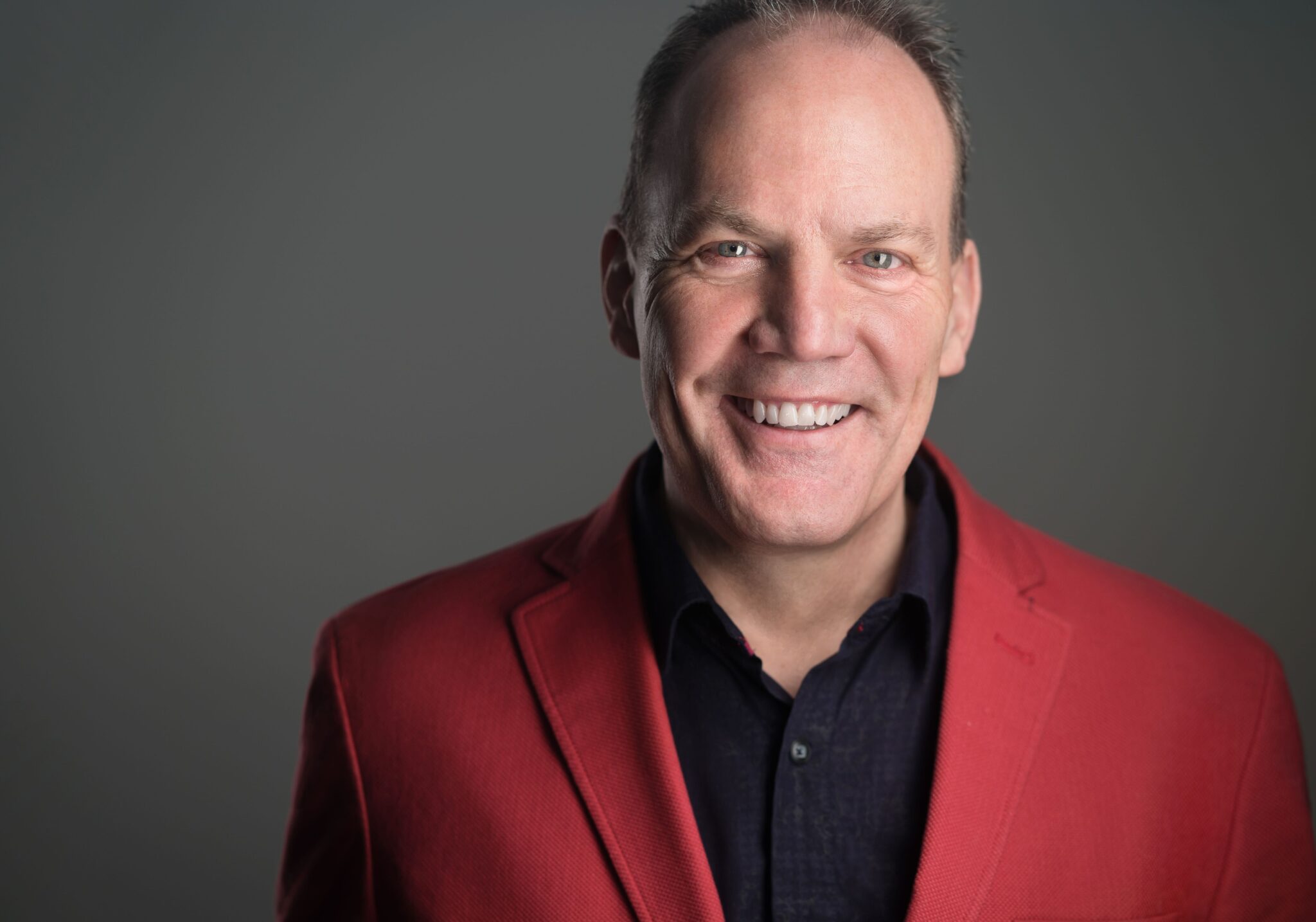 Professional man in red blazer stands for portrait photo.