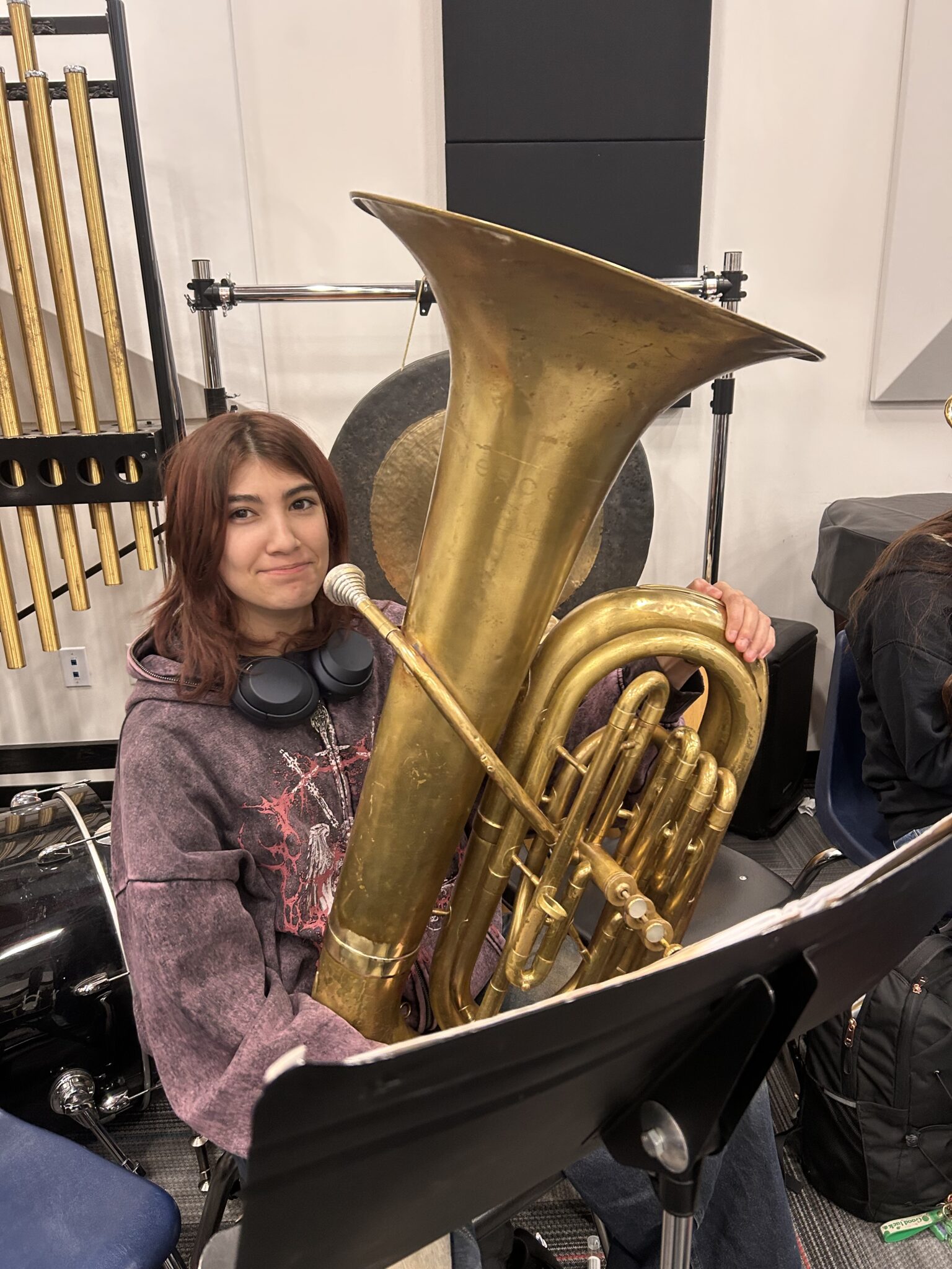 A middle school girl sitting in the band room with her tuba.